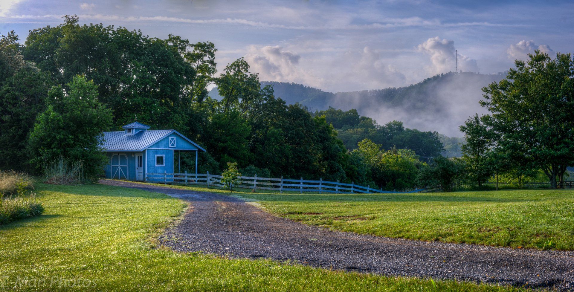A small blue house is sitting in the middle of a grassy field.