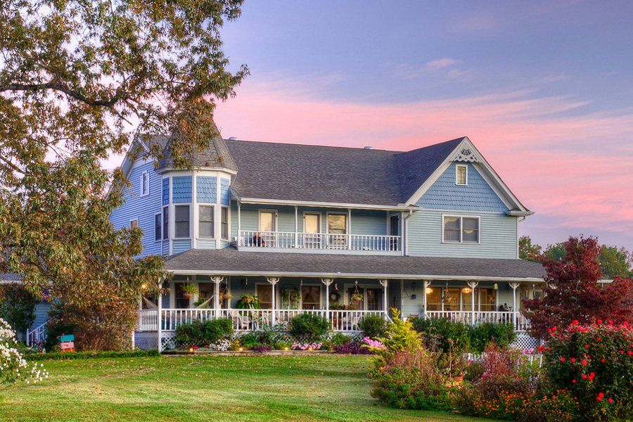 A large blue house with a pink sky in the background