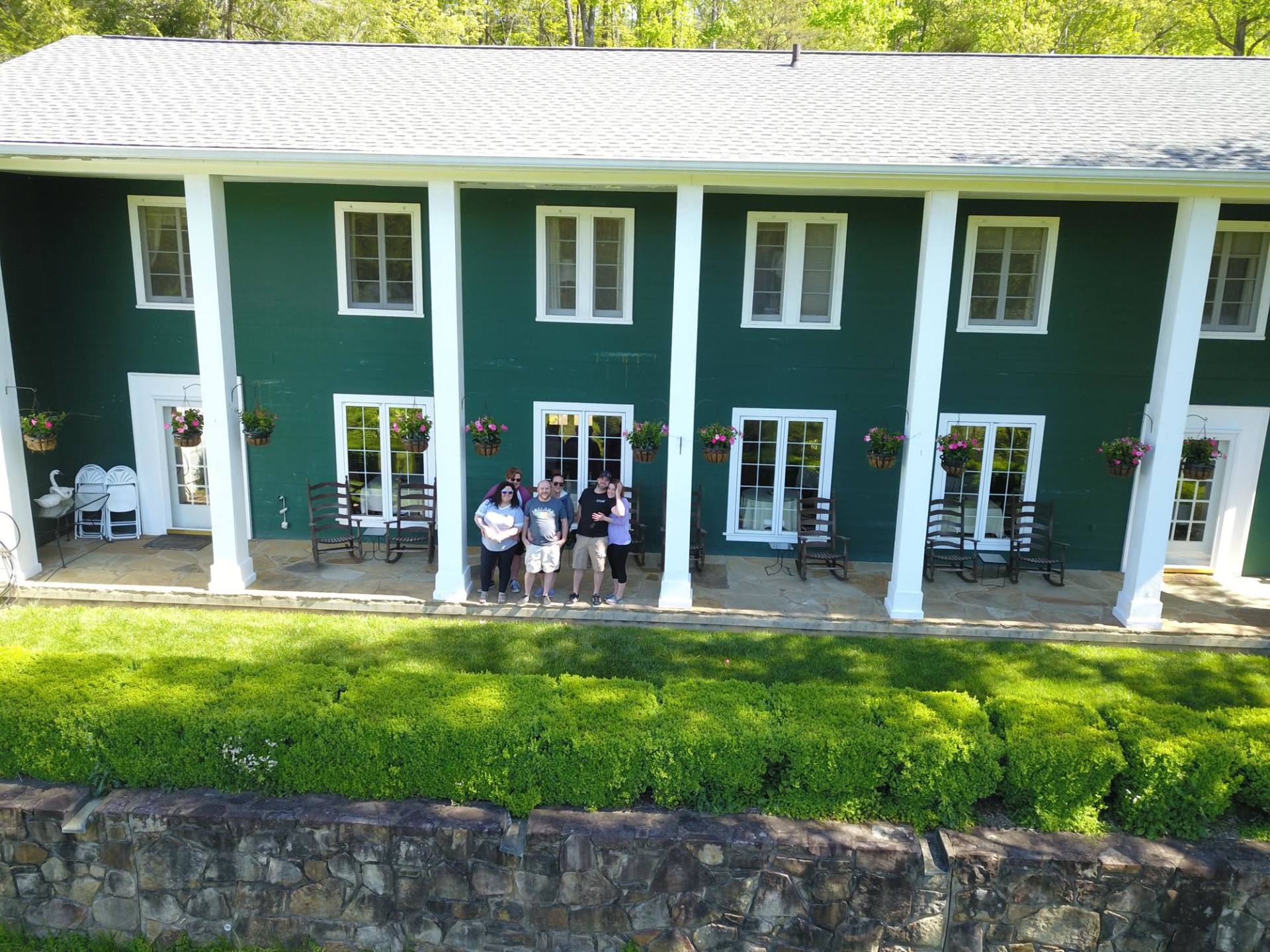 A group of people are posing for a picture in front of a green house.