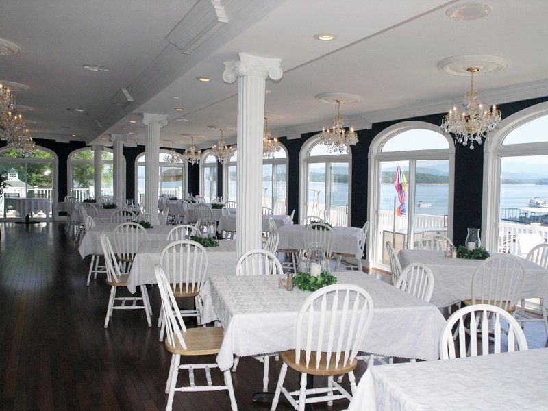 A large dining room with tables and chairs and a view of the water