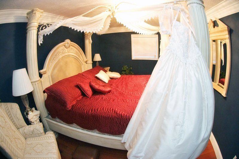 A wedding dress hangs from a canopy over a bed