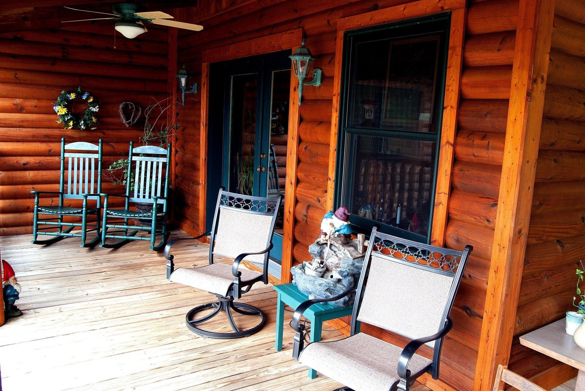 A wooden porch with rocking chairs and a ceiling fan