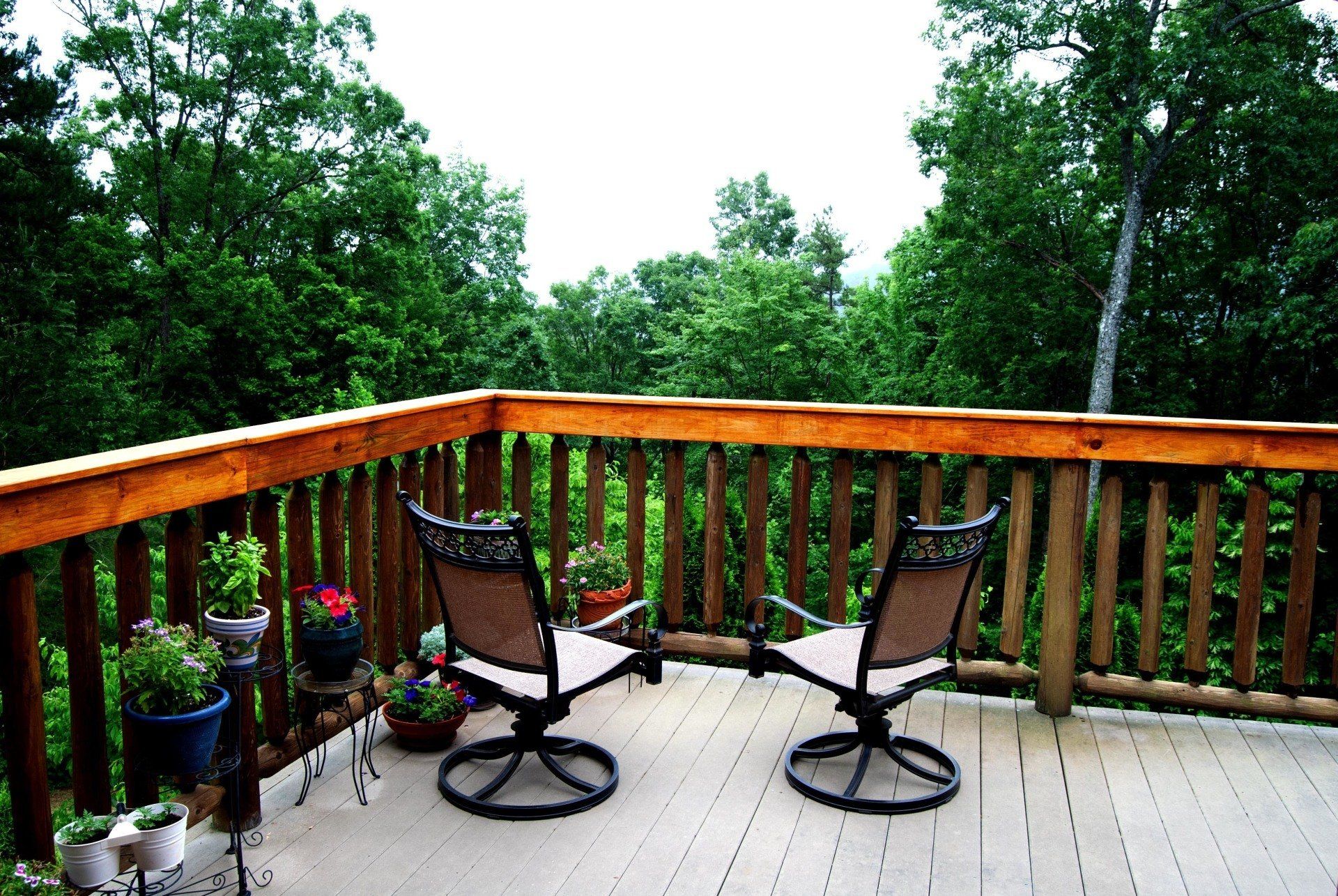 Two chairs on a deck with trees in the background