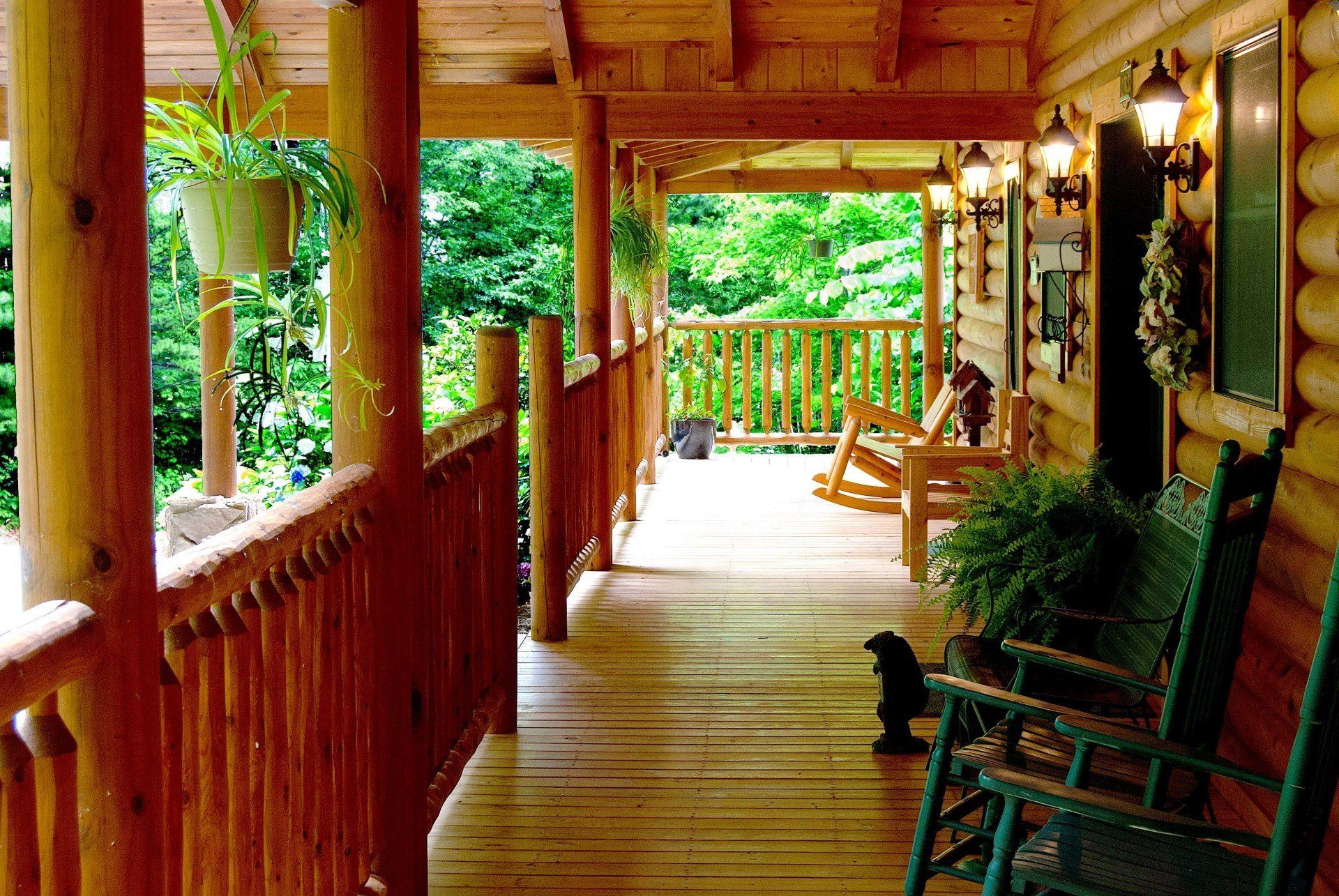 A wooden porch with rocking chairs and a dog
