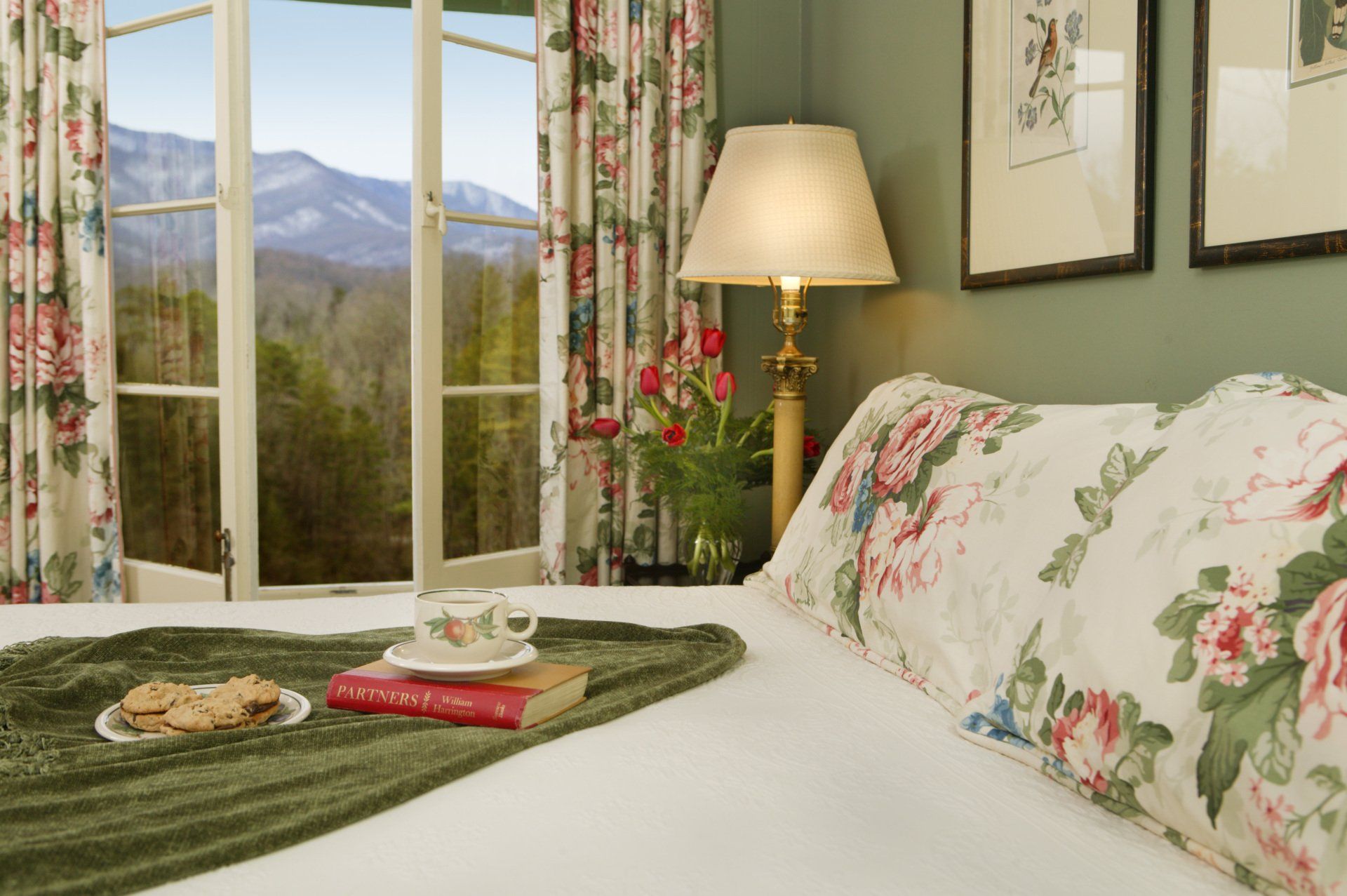 A bed with a tray of cookies and a book on it.