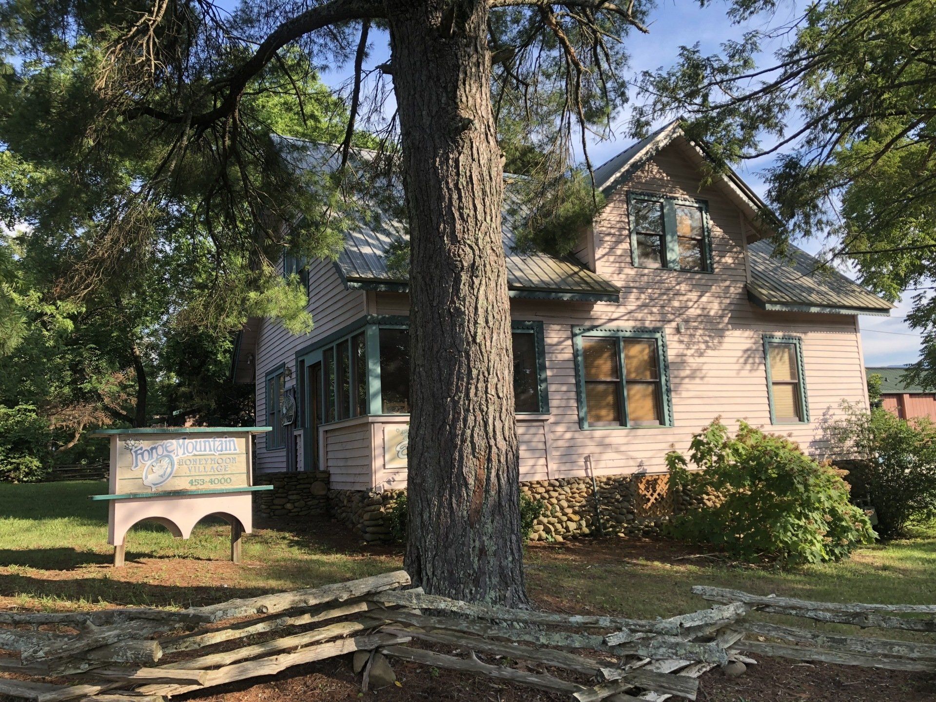 A pink house with a tree in front of it and a wooden fence.