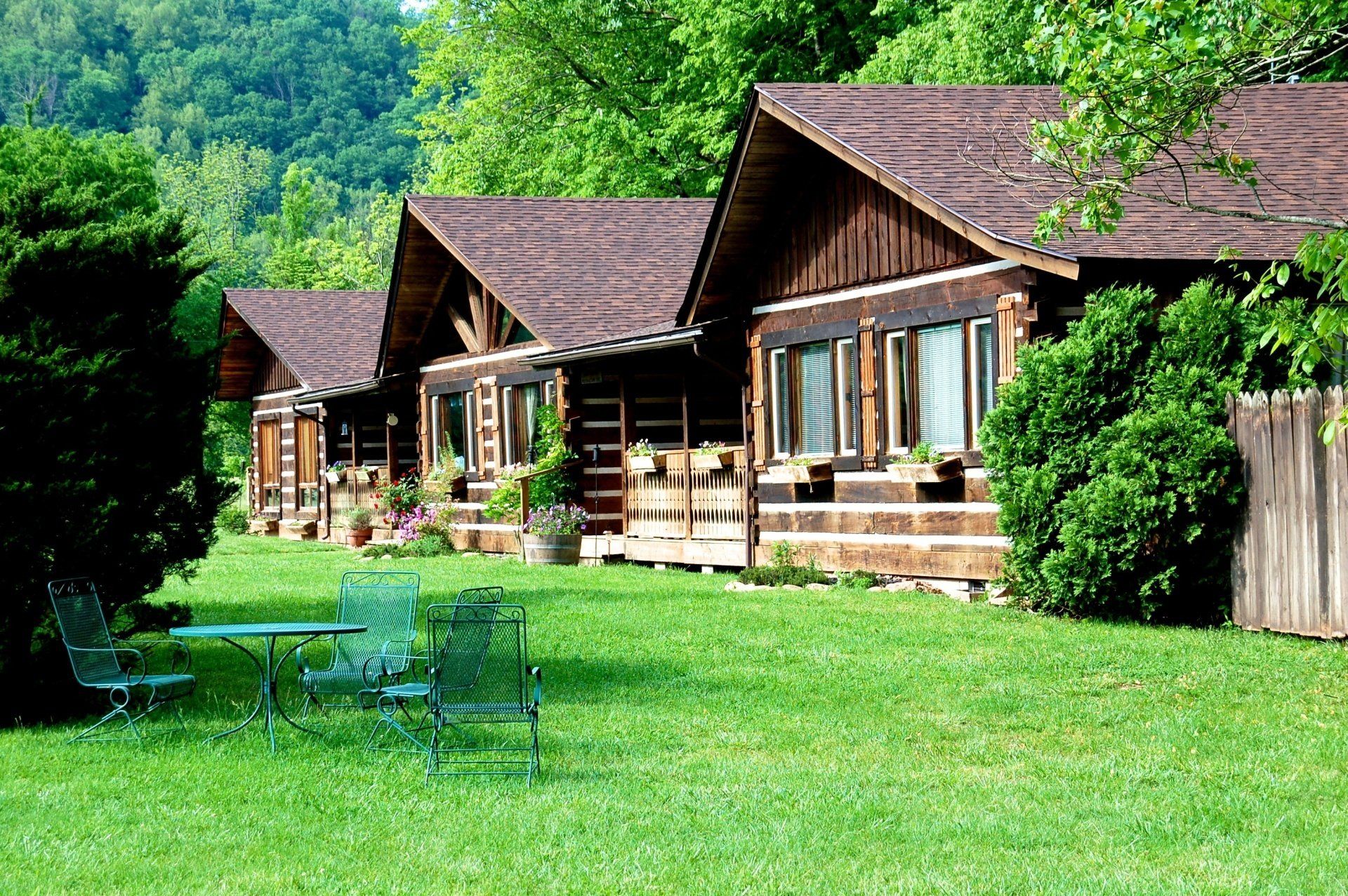 A row of log cabins sitting on top of a lush green field.