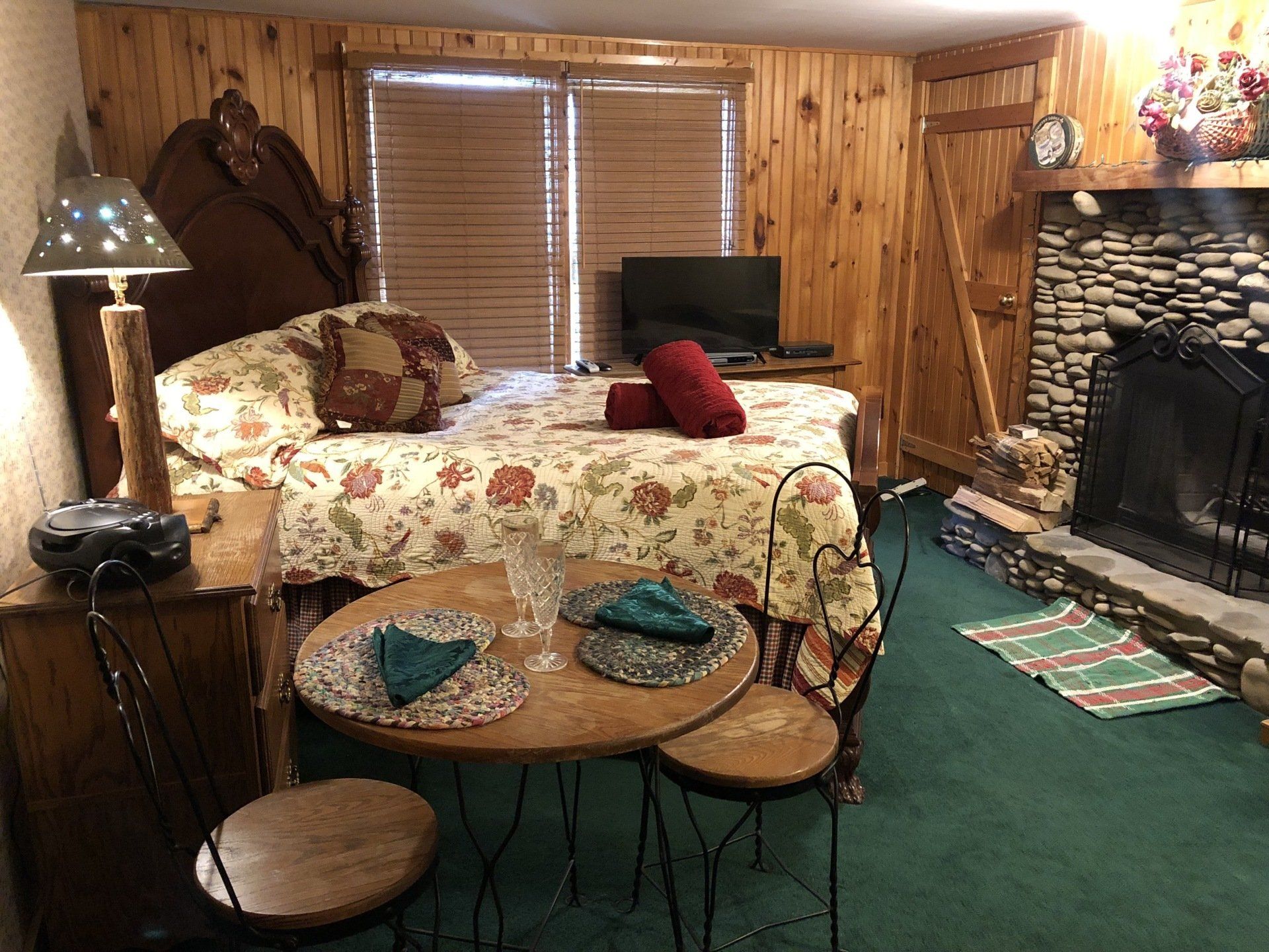 A bedroom with a bed , table and chairs and a fireplace.