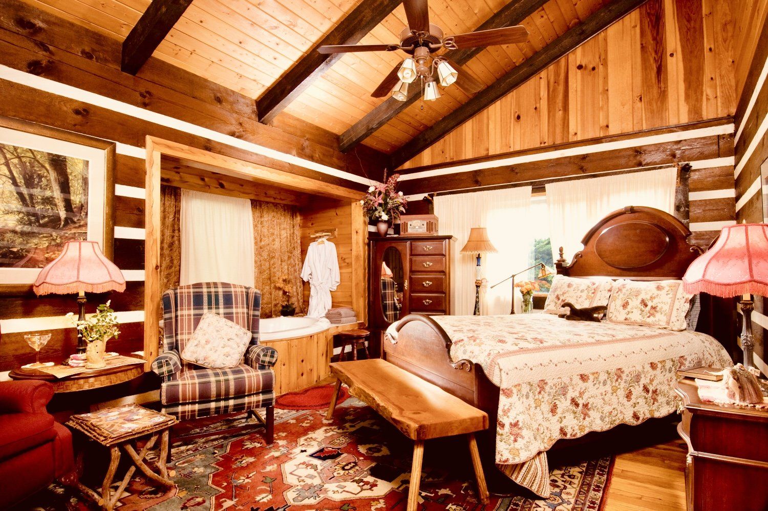 A bedroom in a log cabin with a large bed and a ceiling fan