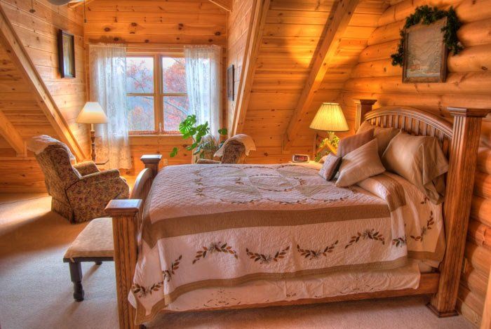 A bedroom in a log cabin with a bed and a window.