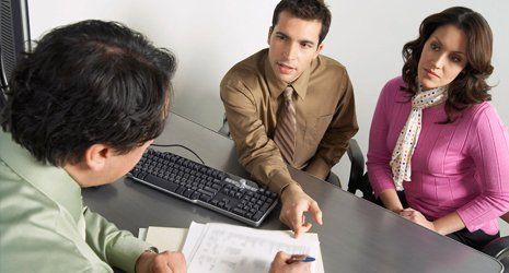 A couple speaking with a man filling in a form