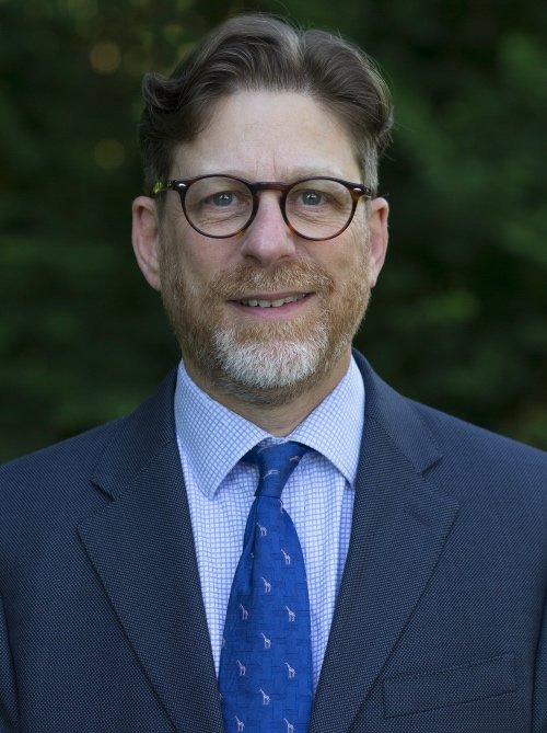 A man in a suit and tie is smiling for the camera