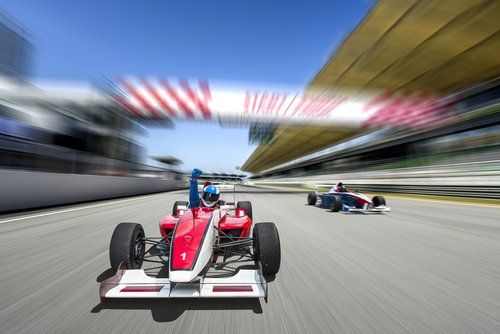 Two race cars are racing on a race track.