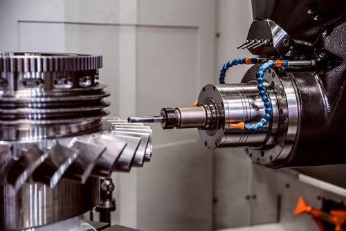 A machine is cutting a metal gear in a factory.