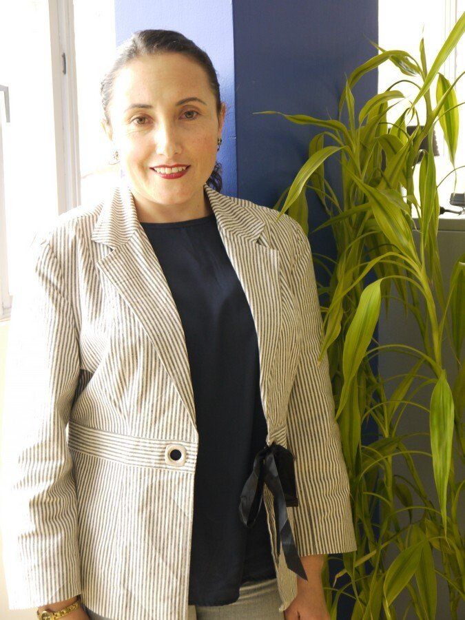 Una mujer con una chaqueta a rayas está parada frente a una planta.