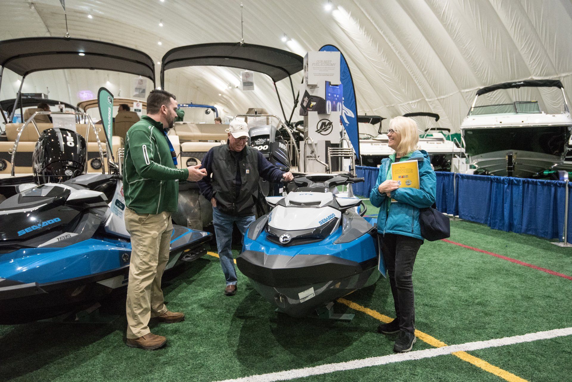 a man and a woman are looking at a jet ski at a boat show .