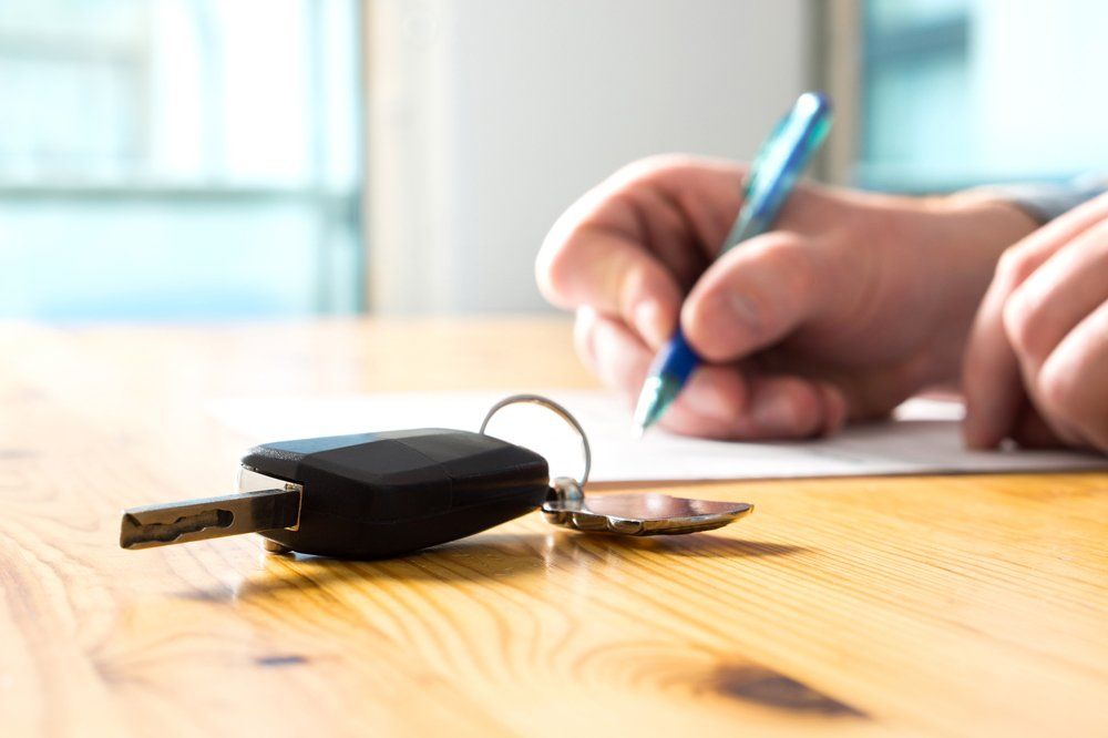 Auto Insurance — Man Signing Car Insurance With Car Keys in Largo, MD