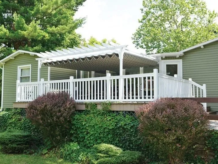 A green house with a white deck and pergola
