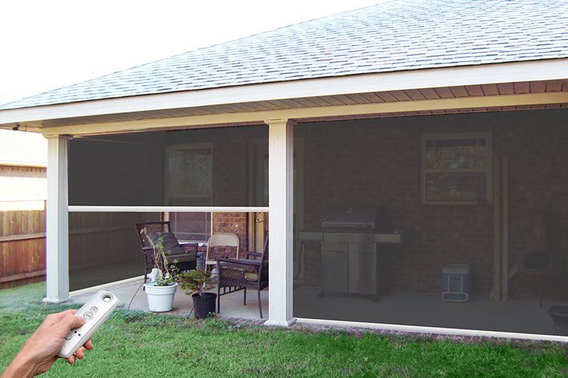 A person is holding a remote control in front of a screened in porch