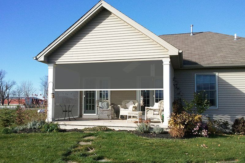 A house with a screened in porch with chairs and a table