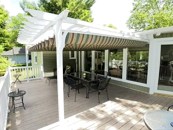 A deck with a pergola and tables and chairs on it.