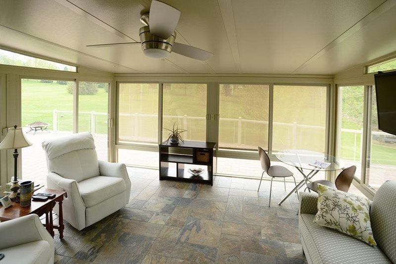 A living room with a lot of windows and a ceiling fan