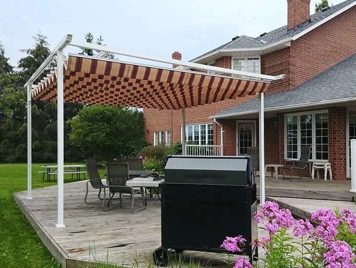 A patio with a canopy and a grill in front of a brick house