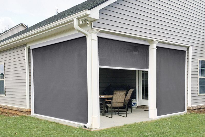 A house with a screened in porch with a table and chairs.