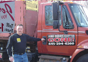 A man standing in front of a junk debris clutter gone truck