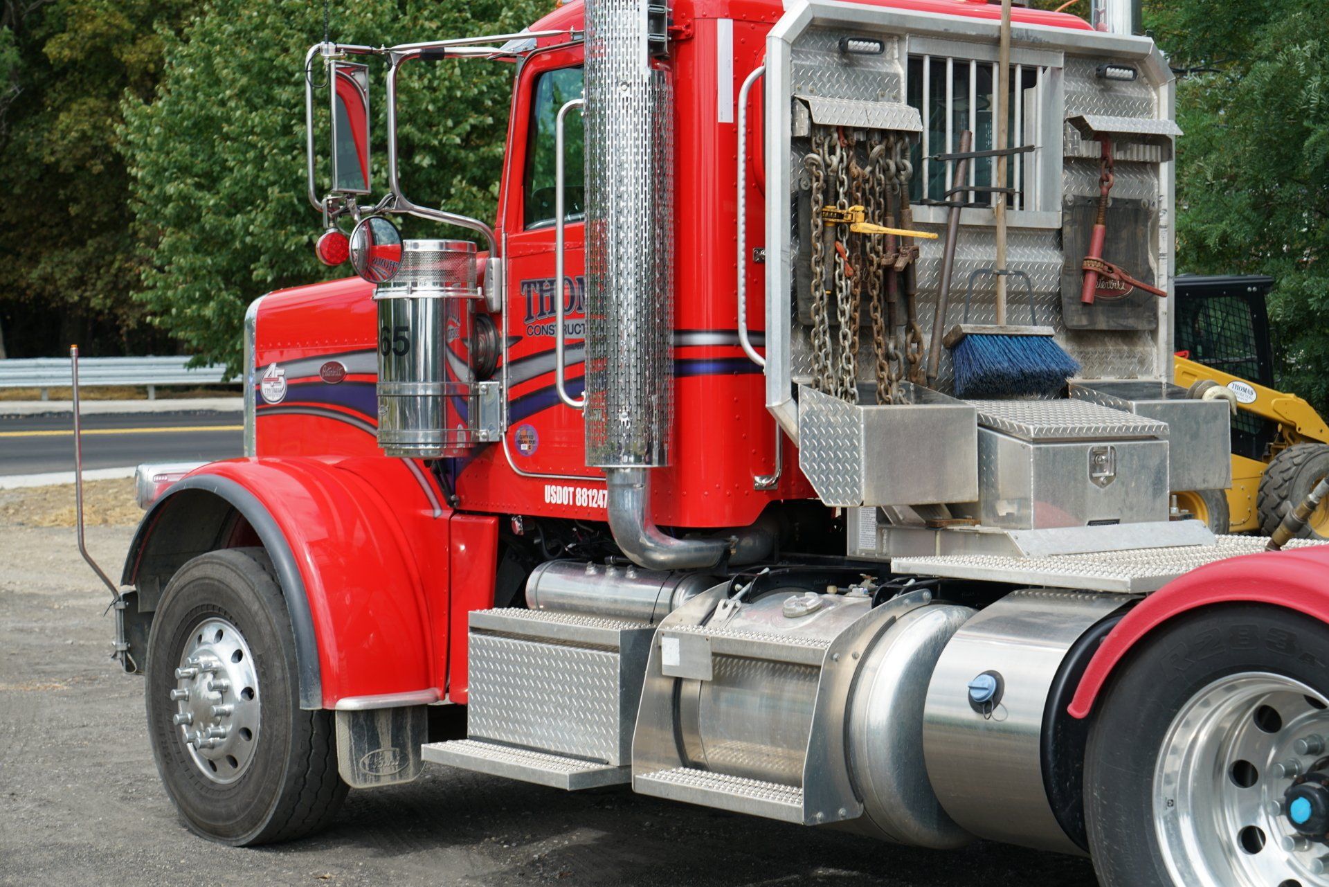 A red semi truck is parked on the side of the road