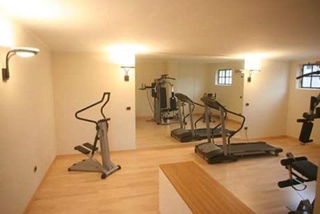 vista interna di una palestra con pavimento in legno e parete gialla