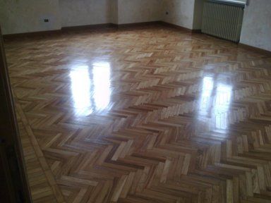 parquet in pavimento di una stanza con parete bianca e luce da sopra