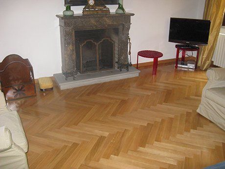 vista interna di una stanza con televisione, camini, angolo di un divano e pavimento in parquet
