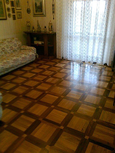 vista interna di una casa con tenda trasparente, divano, mensola in legno e pavimento in parquet