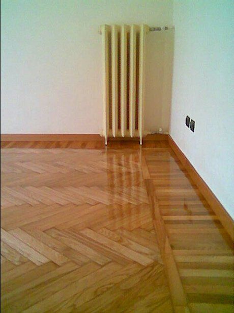 vista laterale di una stanza con parete bianca e pavimento in parquet