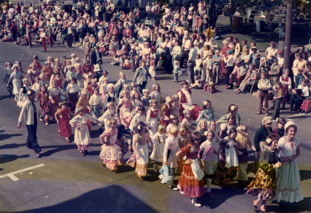 Group of people dressed up for Oktoberfest dancing and making merry.