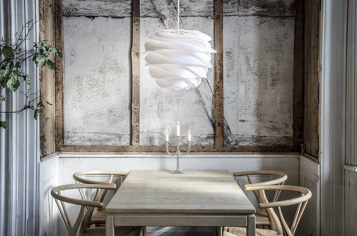 A dining room with a table and chairs and a light hanging from the ceiling.
