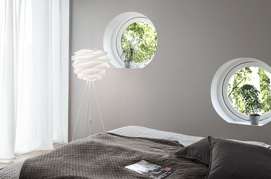 A bedroom with two round windows and a bed.