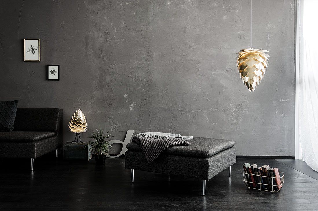 A living room with a couch , ottoman , lamps and a gray wall.