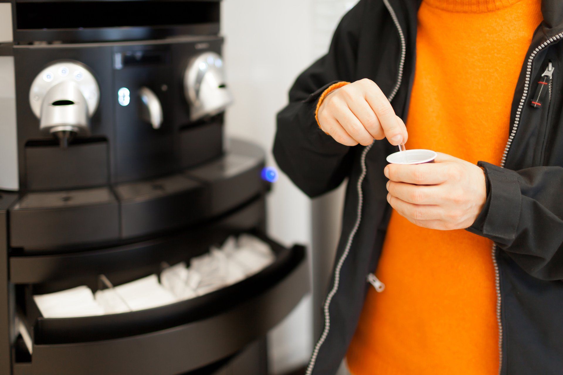 Close-up of a person's hands dispensing a small item from a futuristic vending or service machine.
