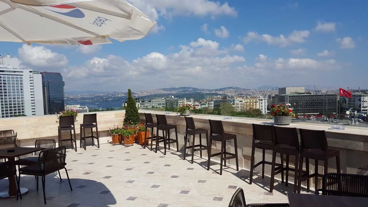 Masalar, sandalyeler ve bir şemsiye ile donatılmış bir çatı verandası.