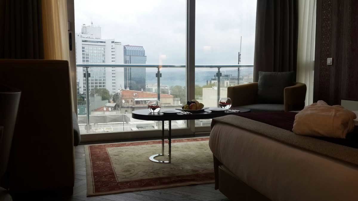 Yatak, sandalye, masa ve balkondan oluşan bir otel odası.