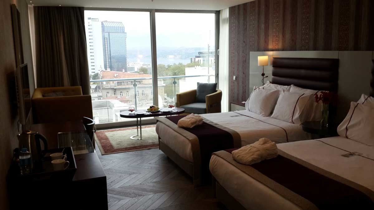 Iki yataklı ve büyük bir pencereli bir otel odası.
