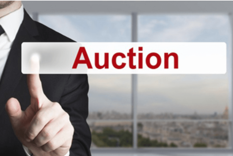 A man in a suit is pressing a button that says auction