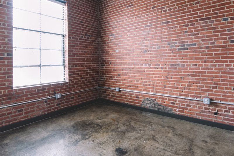 spacious empty room with large window and brick walls