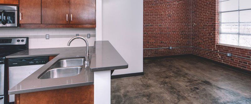 Kitchen sink and counter with spacious dining area with rustic red brick walls