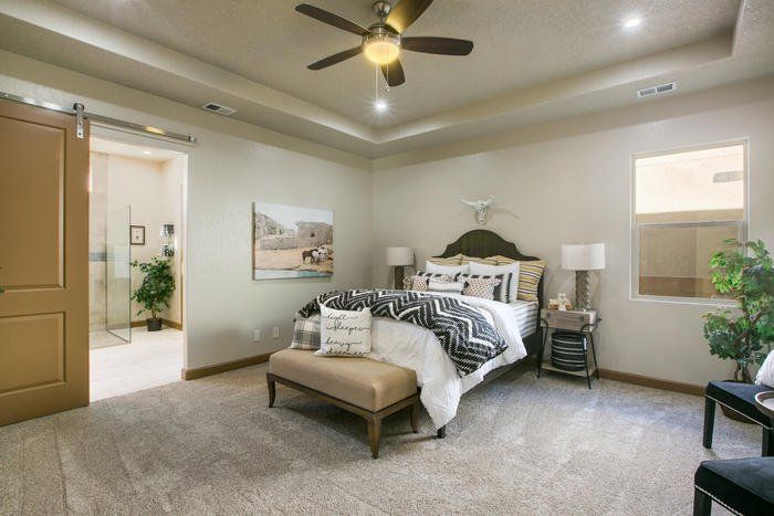A bedroom with a bed , ceiling fan and a sliding barn door.