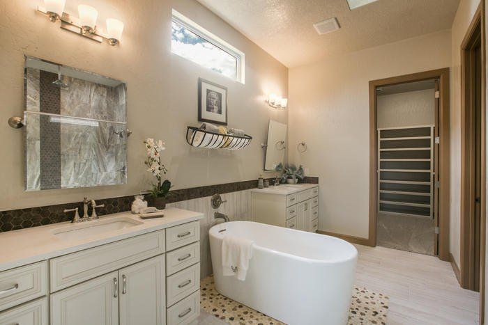A bathroom with two sinks , a tub , and a mirror.