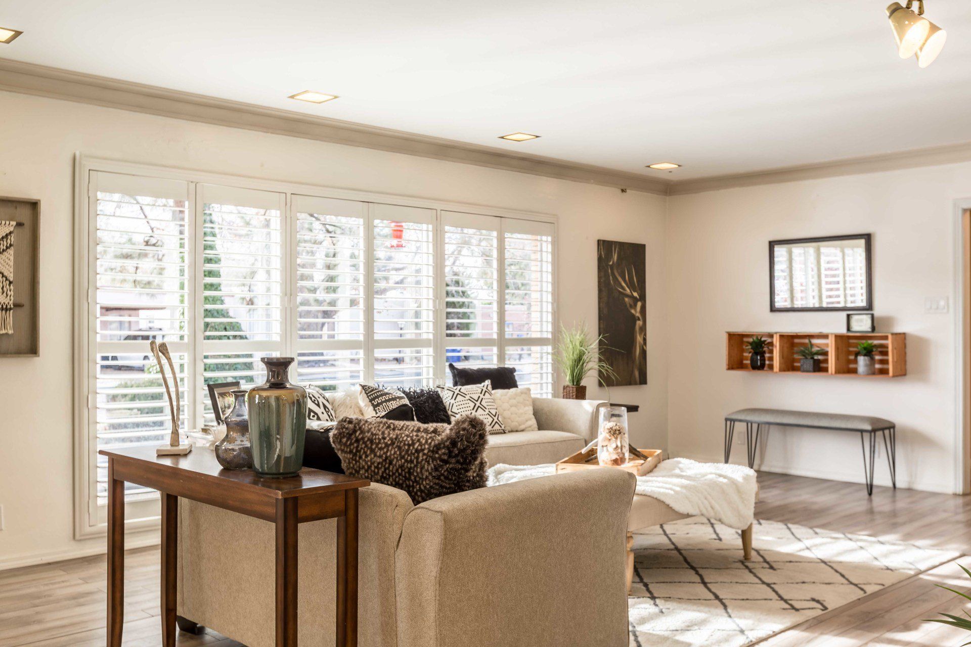 A living room with a couch , chair , table and shutters on the windows.