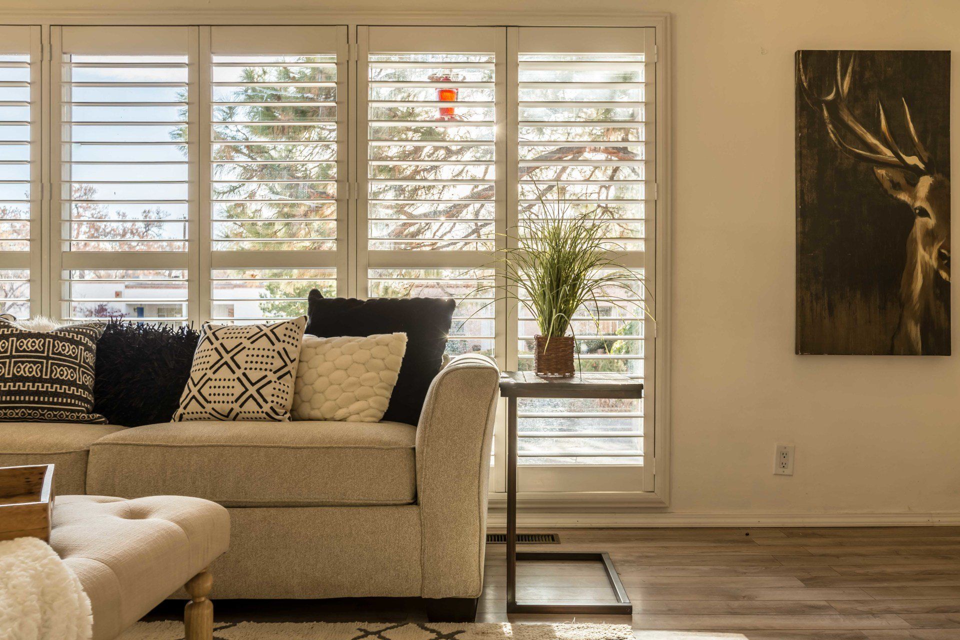 A living room with a couch and a painting of a deer on the wall.